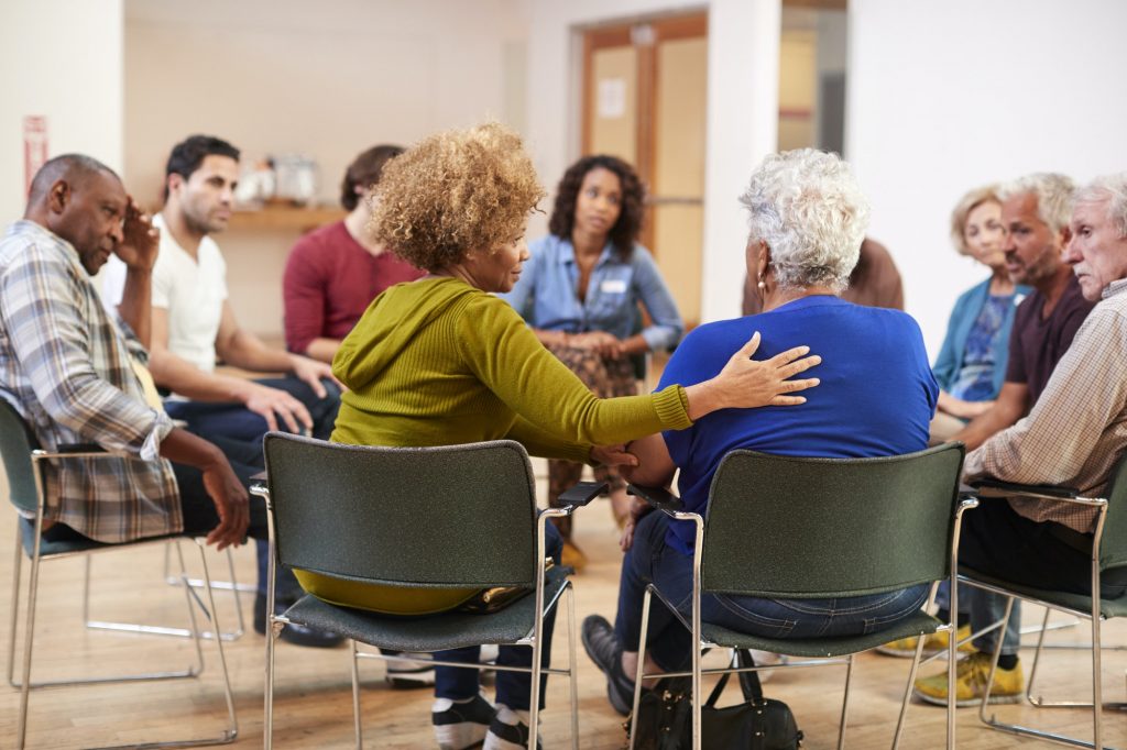 A group of people comfort one another while sitting in a circle. This could represent group therapy in Pasadena, CA. Contact us to learn about our LGBTQ support group, sexual abuse support group, and other services.