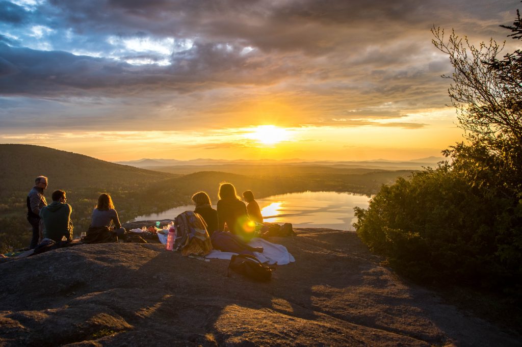 A group of people sit at the edge of a cliff as the sun sets. This could represent group therapy in Pasadena, CA. Contact our LGBTQ support group or learn more about our sexual abuse support group today!