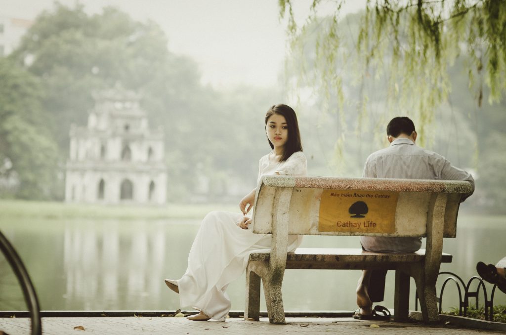 A couple sit on a park bench next to a lake facing away from one another. This could represent the pain of affair recovery. Learn more about affair recovery in Sacramento, CA or affair recovery in Pasadena, CA from an affair recovery therapist in Sacramento, CA. Affair recovery counseling can help your relationship survive & thrive. 95814 | 95688 | 95765