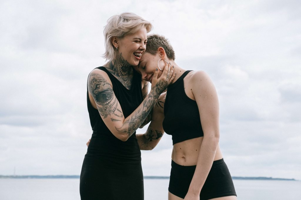 A lesbian couple embrace while laughing representing an improved connection gained through PACT Couples Therapy in Pasadena, CA.