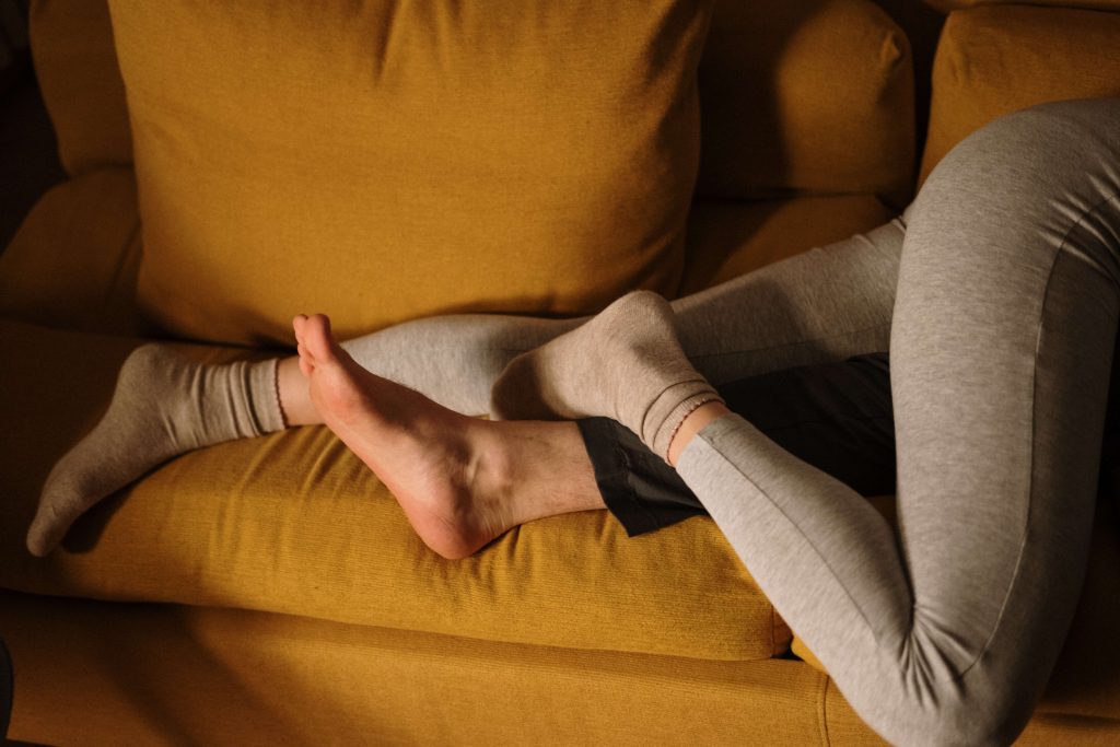 A couple lies on the couch together with their legs entwined representing the improved intimacy that comes with Marriage Counseling in Pasadena, CA.